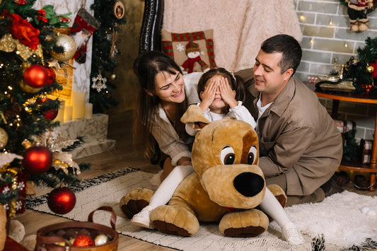 A man and a woman sitting on the floor with a large teddy bear