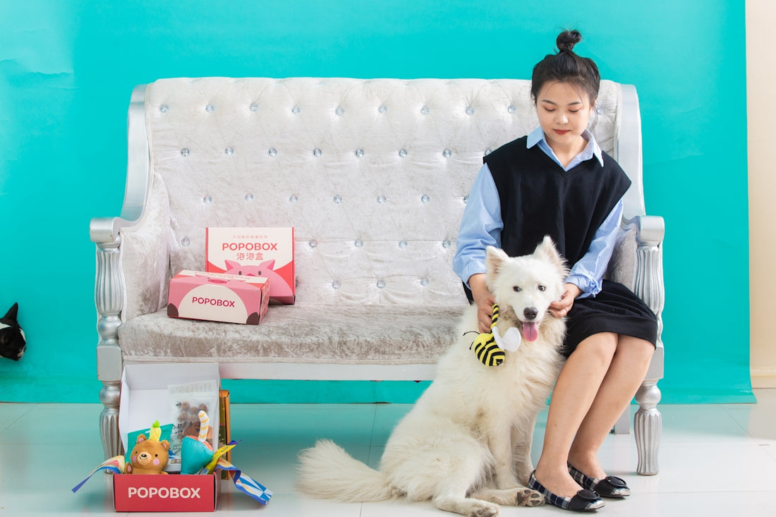 A woman sits with a dog, posing.