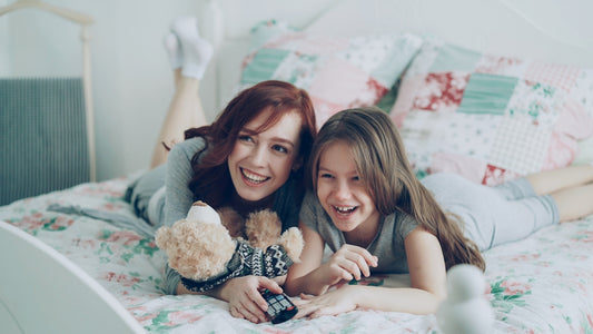 Two girls laugh while relaxing on a bed