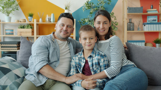 A happy family of three sitting on a couch