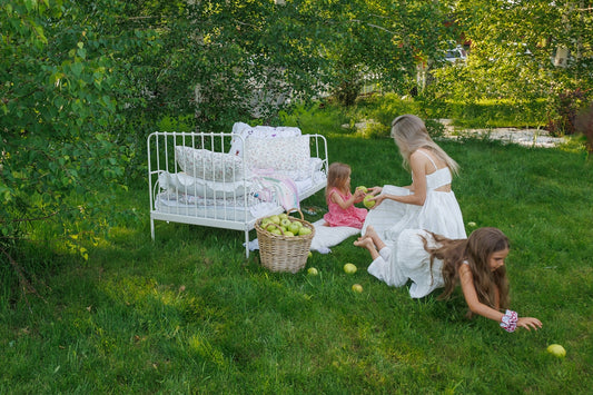 Mother and children picking apples in a garden.
