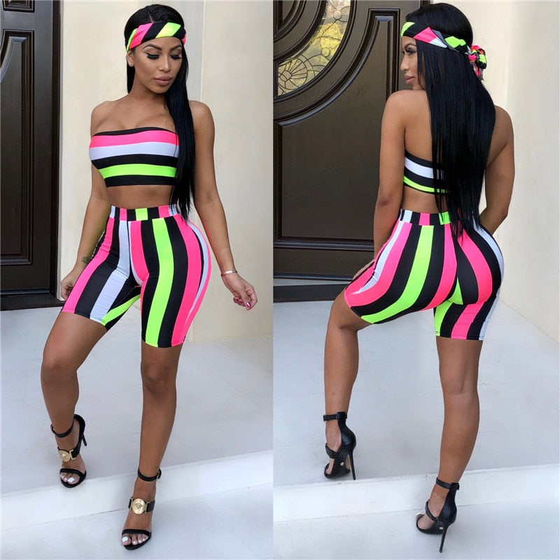 A woman models the Women's Striped Two-Piece Summer Set—featuring a strapless crop top, high-waisted shorts in neon stripes, a matching headscarf, and black heels—posing to show both front and back views.