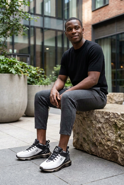 Black male model seated outdoors wearing white-and-black trainers with smoky translucent air-pocket soles.