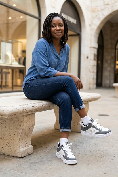 Model wearing grey-and-white lace-up trainers with dark jeans