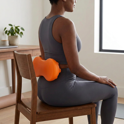 Black woman seated with the orange lumbar massage board positioned at her lower back